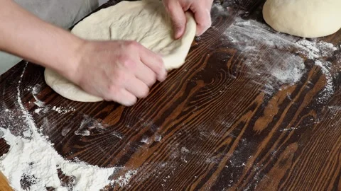 Hands stretching and shaping fermented pizza dough into flatbread on floured Stock Footage 310337400