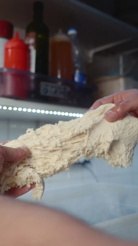 Hands stretching bread dough during preparation Stock Footage 344313033