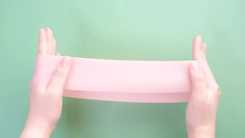 Hands stretching fitness elastic band on green background close-up. Stock Footage 288288207