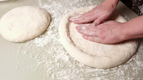 Hands stretching raw pizza dough on a floured surface for homemade baking Stock Footage 330761332