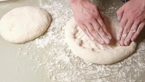 Hands stretching raw pizza dough on a floured surface for baking Stock Footage 330761349