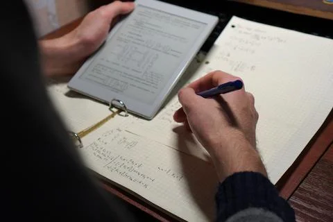 The hands of a student with a ballpoint pen solving math problems before a .. Fotos de archivo