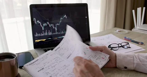 The hands of student flip through the pages of a notebook with a trading chart Stock Footage 162180798