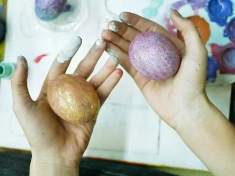 In the hands of the student painted eggs for Easter, background palette Stock Photos