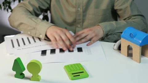 Hands study statistical charts and calculate figures alongside eco-friendly tree Stock Footage 316038793