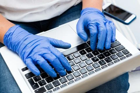 Hands with surgical gloves typing on a laptop keyboard Stock Photos
