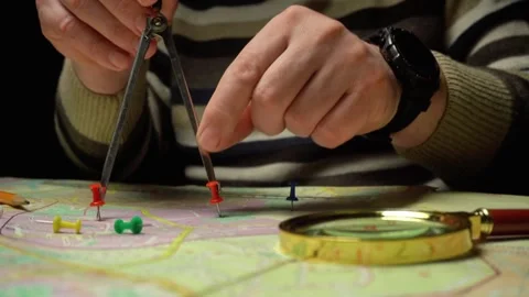 Hands of a surveyor using a compass to measure distances on a map with colorful Stock Footage 332616050