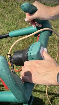 Hands switch on the handle of the lawn mower Stock Photos