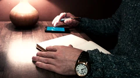 Hands on the table working on a smartphone and write a pen to notebook Stock Footage 56250565