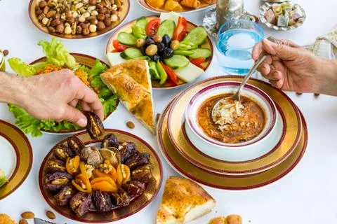 Hands take dry date fruit and soup on Ramadan Table Stock Photos