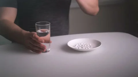 Hands take a pill from a full plate of medicines, then take a glass of water Stock Footage 168911184