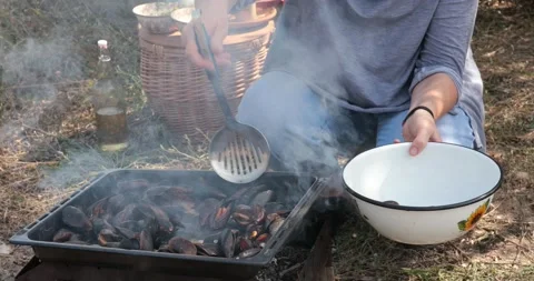Hands take off seafood mussels in shells from barbecue into bowl Stock Footage 165079433