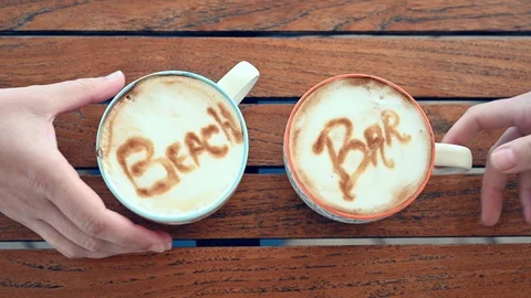 Hands take two cups of cappuccino with the words beach and bar Stock Footage 107792896