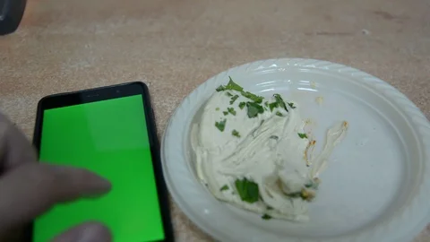 Hands takes hummus with bread from plastic plate, cell phone with chromakey. 스톡 동영상 99766311