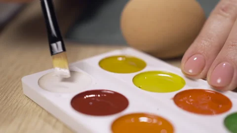 Hands takes white paint for coloring easter eggs with painting brush. Stock Footage 329068420
