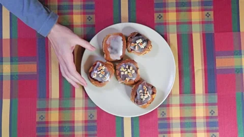 Hands Taking Cinnamon Rolls from Plate on Colorful Table Stockbeeldmateriaal 291688401