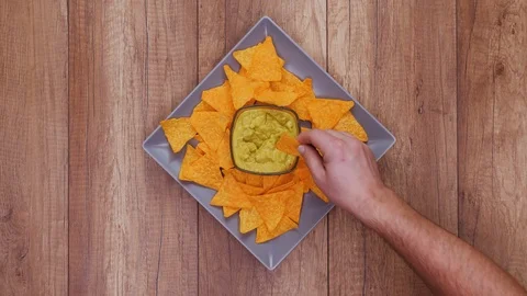 Hands taking delicious tortilla chips from a rotating plate 스톡 동영상 124612629
