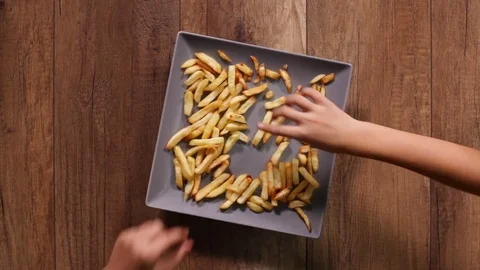 Hands taking french fries from a rectangular plate rushing to consume Video stock 82852884