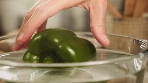 Hands taking green bell pepper from water in slow motion Stock Footage 152904385