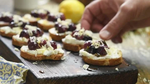 Hands taking the prepared roasted grapes crostini. Stock Footage 202176817