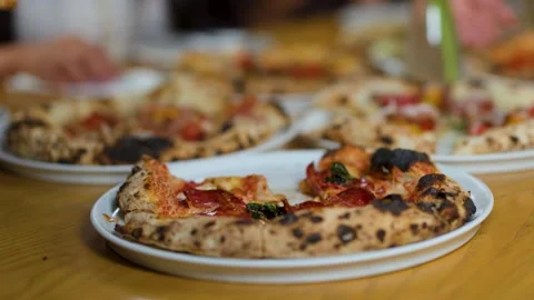 Hands Taking Slices of Neapolitan Pizza at a Restaurant Table Stockbeeldmateriaal 337519548