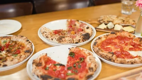 Hands Taking Slices of Neapolitan Pizza at a Restaurant Table 스톡 동영상 338420290