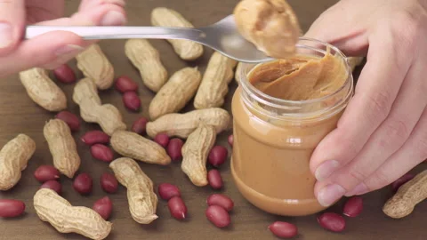 Hands taking a spoon of peanut butter from a jar Stock Footage 311750601