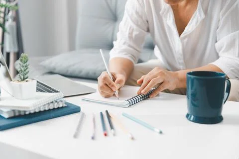 Hands taking study notes in spiral notebook beside laptop, colorful pens an.. Stock Photos