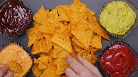 Hands taking tortilla chips dipping them in various flavoured sauces 動画素材 154894876