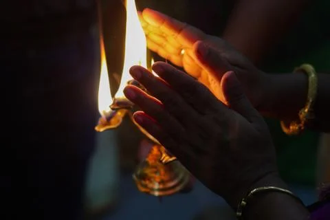 Hands taking warmth of Divine diya holy flame of hindu god worship puja for b Stock Photos