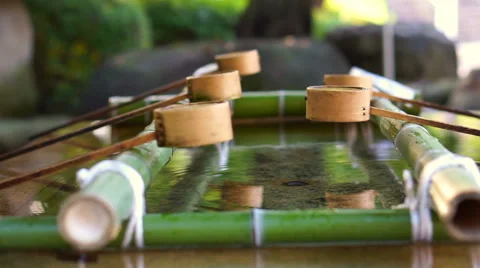 Hands taking water with ladle to clean hand before entering Japanese temple Stock Footage