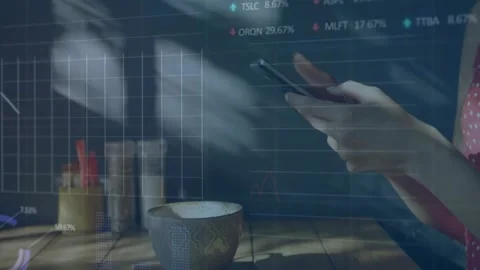 Hands tapping and swiping phone on table, causing stock charts to overlay view Stock Footage 334036483