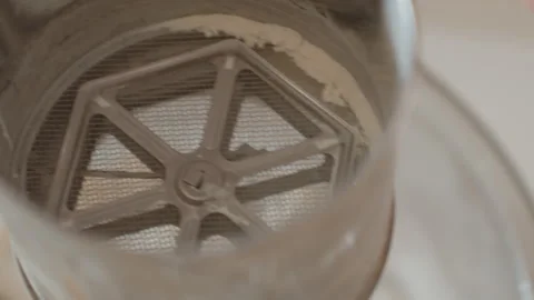 Hands tapping reusable stainless steel coffee filter to release grounds through Stock Footage 343675810