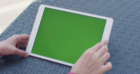 Hands tapping tablet with green screen mockup on modern outdoor table close-up Stock Footage 345448435