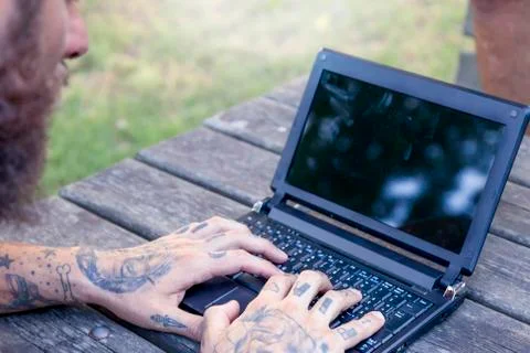 Hands of a tattooted man working with computer outdoor Stock Photos