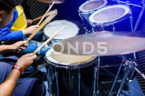 Hands of teacher with wooden drumsticks guiding boy in drum learning tutorial Stock Photos