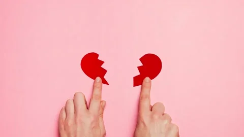 Hands tear apart the shape of a red heart on pink background. Broken heart Stock Footage 146095960