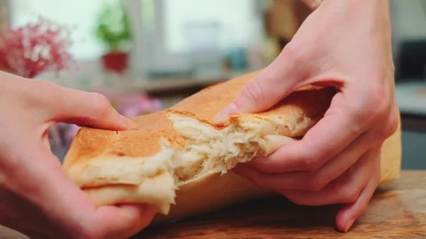 Hands tearing fresh baked bread on wooden table in kitchen daytime Stock Footage 342878980