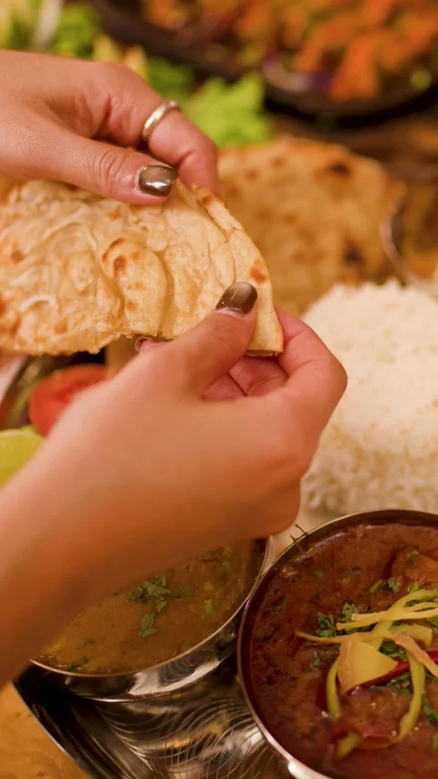 Hands Tearing Fresh Naan Bread Over Indian Thali Platter Video stock 337519969