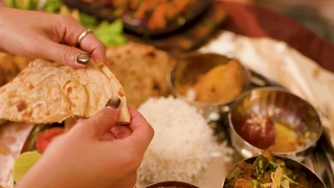 Hands Tearing Fresh Naan Bread Over Traditional Indian Thali Platter Video stock 337520068