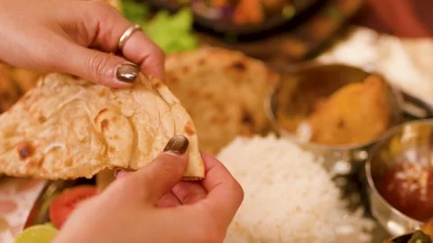 Hands Tearing Fresh Naan Bread Over Traditional Indian Thali Platter Video stock 337768757