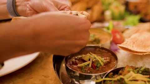 Hands Tearing Naan Bread to Dip in Indian Curry Thali Video stock 337746947
