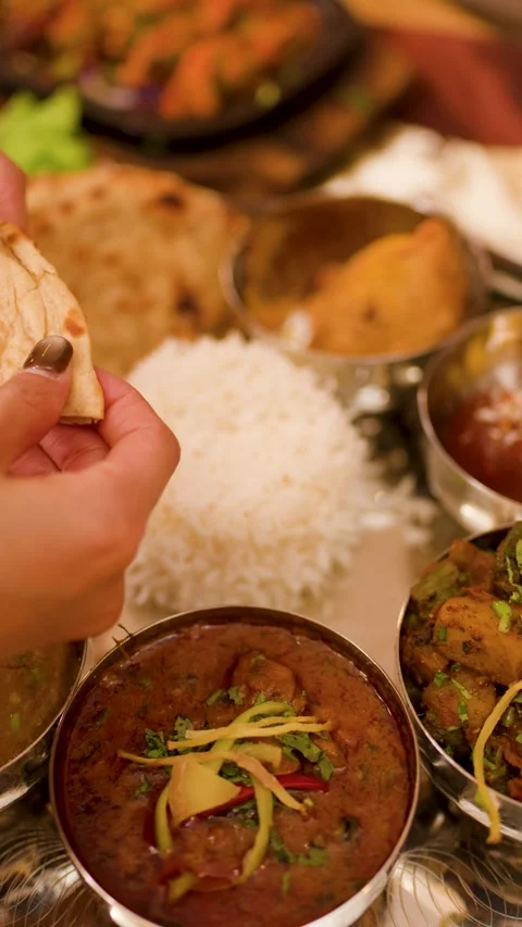 Hands Tearing Naan Bread Over Traditional Indian Thali Platter Stock Footage 340182987