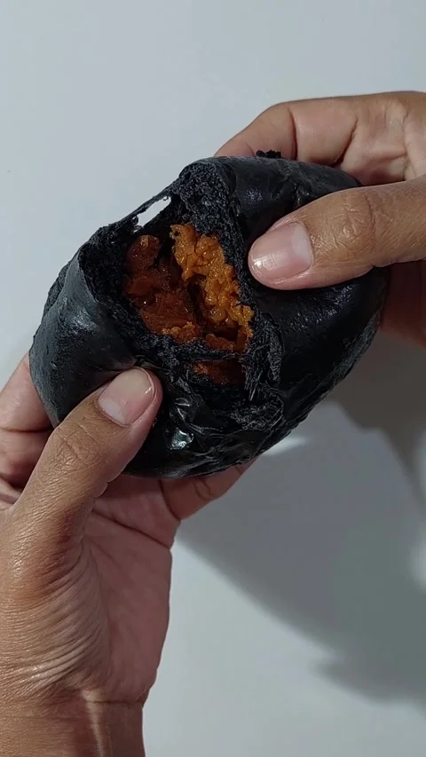 Hands tearing Thai tea custard charcoal bun Stock Footage 279807778