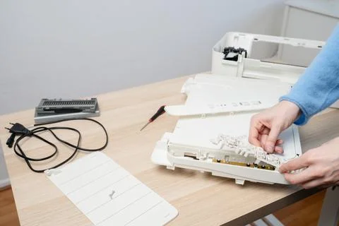 Hands of a technician disassembling a flatbed scanner printer on a wooden des Stock Photos