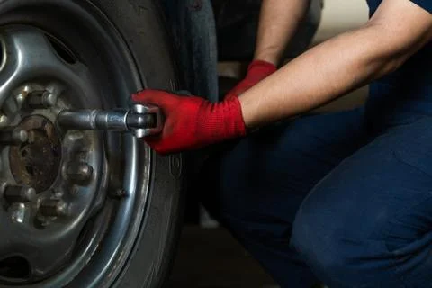 Hands of technician using a torque wrench to remove car wheel bolts - Low view Stock Photos