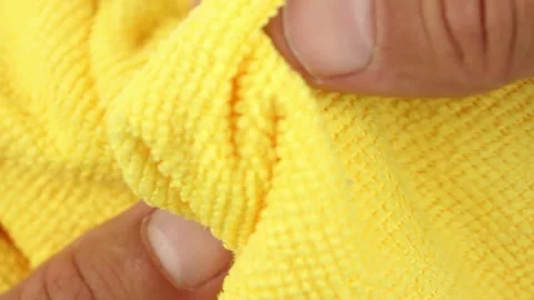 Hands testing and stretches yellow microfiber dusting cloth, close-up texture Video stock 160053254
