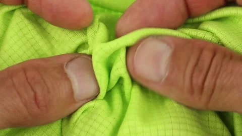 Hands testing, crushes and stretches green sports breathable synthetic fabric Video stock 158768927