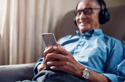 Hands, texting and old man with phone in lounge, smile or listen to music w.. Stock Photos