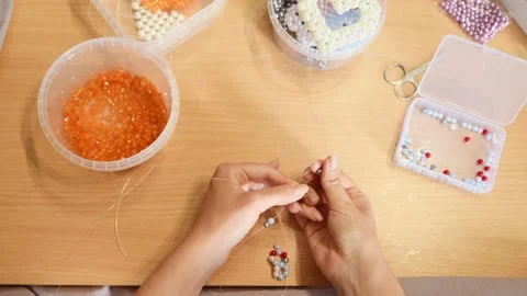 Hands threading colorful small beads into intricate beadwork on wooden tabl.. Video stock 339566291